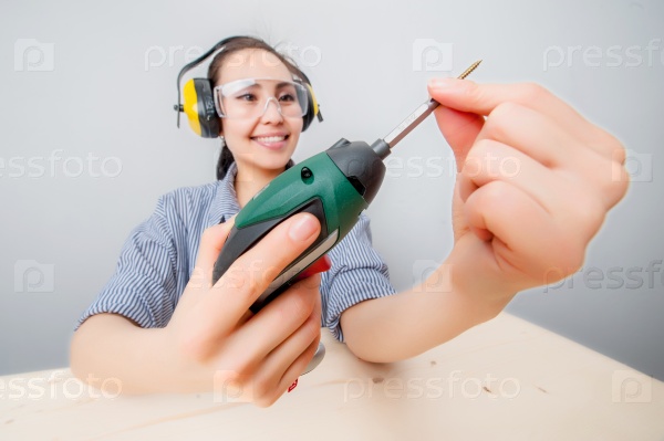 Young woman with a drill at home, stock photo