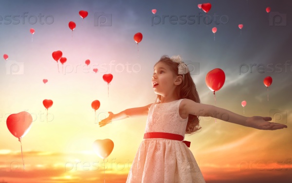Sweet child girl looking at red balloons. Balloons in shape of heart flying in the sunset sky. Wedding, Valentine, love concept.