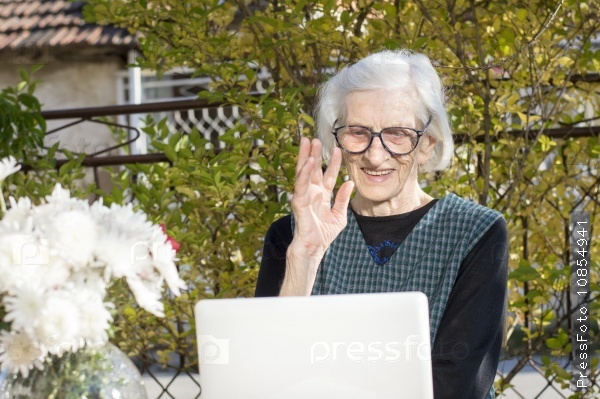 90 years old woman waving while having a a video call