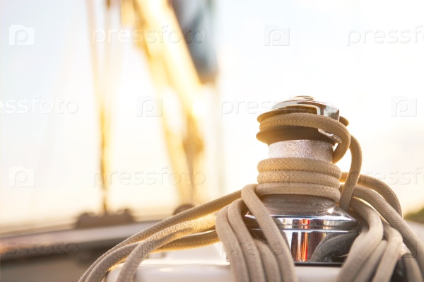 Sailboat detailed parts. Close up on winch and rope of yacht over blue sea. Yachting concept. Shallow depth of field