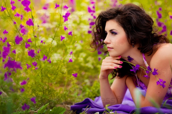 Beautiful young woman lying in purple flowers outdoors