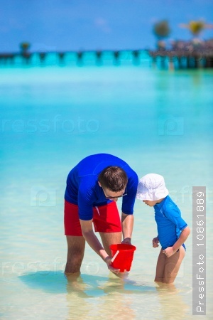 Father and little girl catching fish on tropical beach