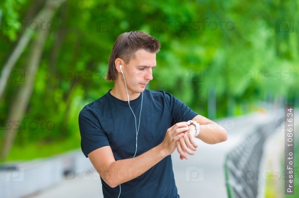 Runner looking at smart watch heart rate monitor having break while running