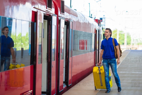Young caucasian man with luggage at station traveling by train
