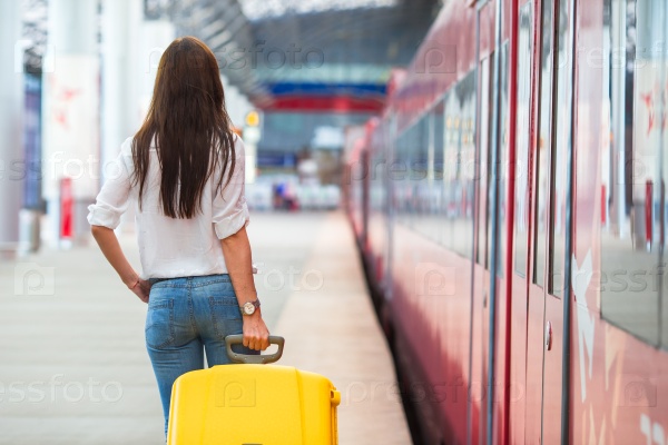 Young caucasian girl with luggage at station traveling by train
