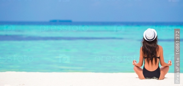 Young woman sitting in yoga position during tropical vacation