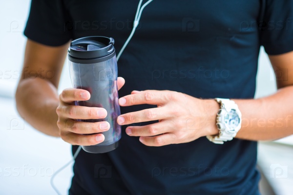 Close-up smart watch heart rate monitor and bottle of water in male hands