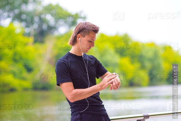 Runner looking at smart watch heart rate monitor having break while running, stock photo