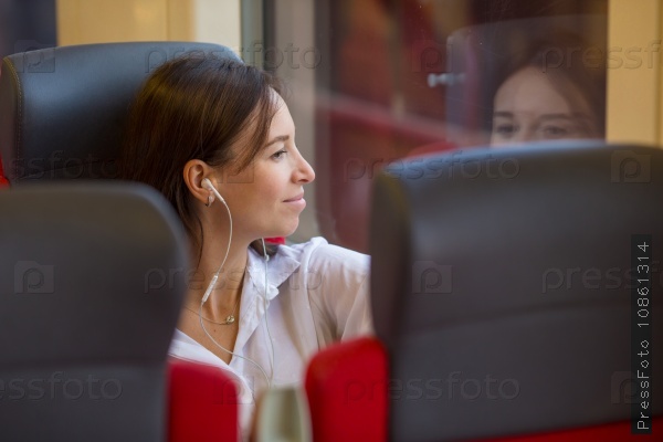 Young happy girl listening music traveling by train