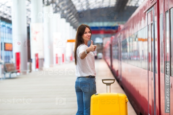 Young caucasian woman with luggage at station traveling by train, stock photo