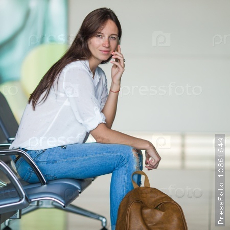 Young woman talking on the phone while waiting boarding, stock photo