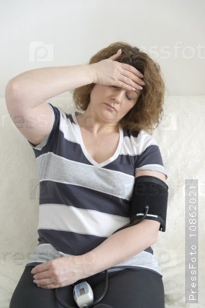 Woman with headache measures a blood pressure