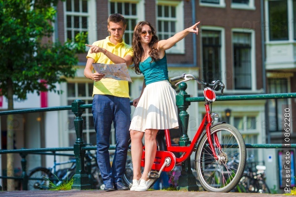 Young tourists couple looking at map with bikes in european city