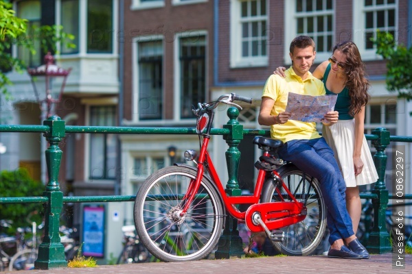 Young tourists couple looking at map with bikes in european city