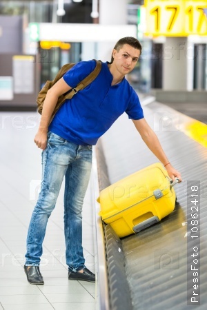 Young man taking the luggage from the belt at airport