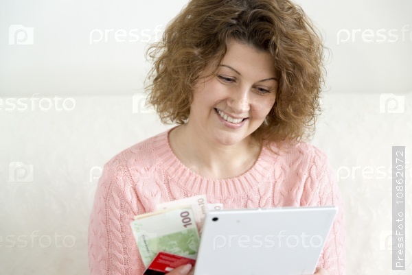 Woman with tablet pc computer and credit card and money at home, stock photo
