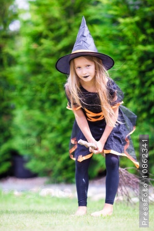 Adorable little girl wearing witch costume with broom on Halloween outdoors