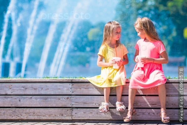Little happy girls have fun near street fountain at hot sunny day