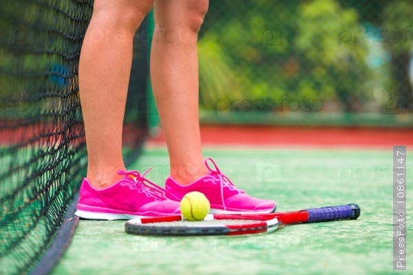 Closeup of shoes with the tennis racquet and ball outdoors on court, stock photo