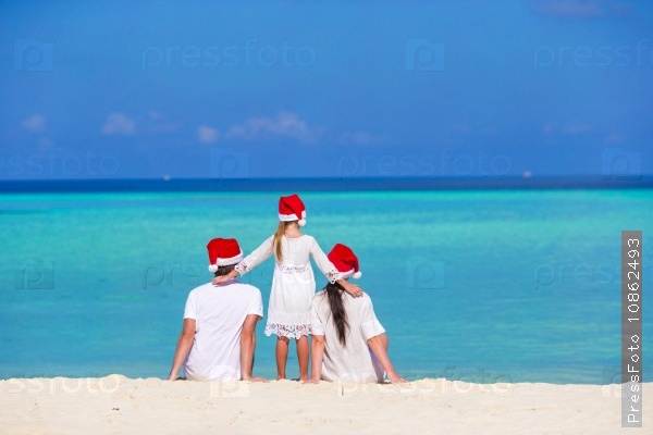 Happy family in Santa Hats on beach during Christmas vacation