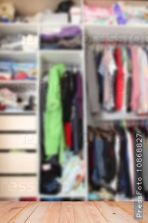 Blurred picture of wardrobe with clothes on the wooden surface