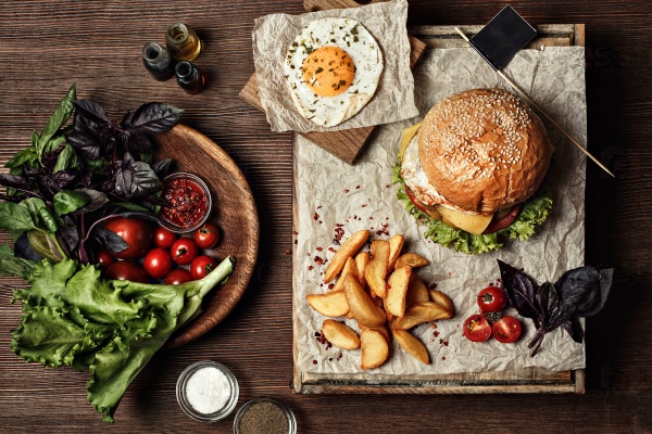 Veggie burger with salad, tomato and fries. Wooden background