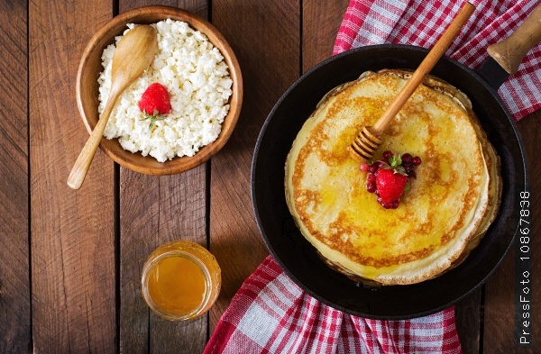 Golden pancakes with cranberry jam and honey in a rustic style. Top view, stock photo