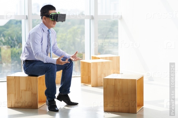 Businessman in virtual reality glasses talking to invisible partner
