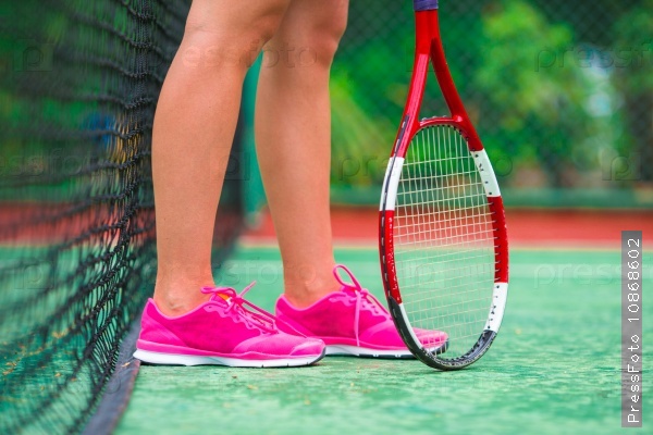 Closeup of shoes with the tennis racquet and ball outdoors
