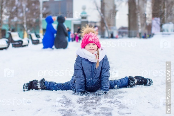 Adorable fashion little girl skating on the ice rink outdoors, stock photo