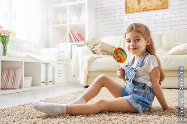 Funny child girl plays at home. girl eating candy and resting. recreation and entertainment at home, stock photo