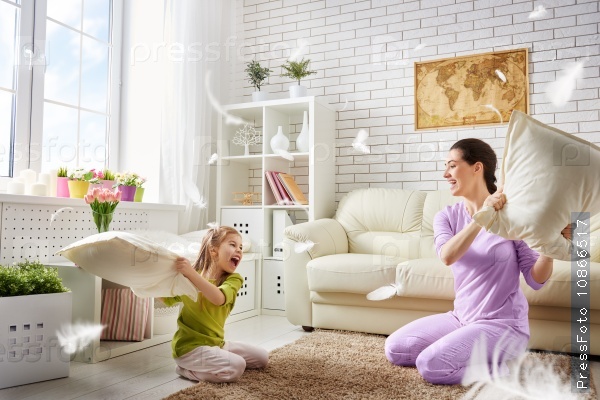 Happy family! The mother and her child girl are fighting pillows. Happy family games.