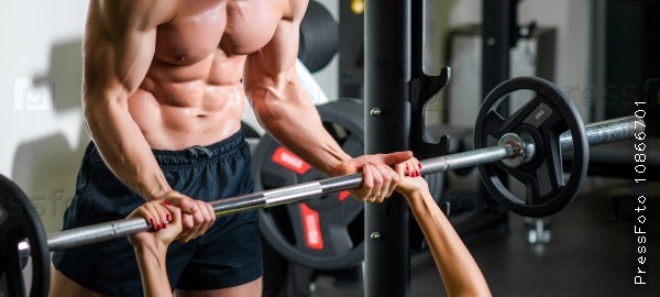 Weightlifting and people concept - personal trainer with barbell flexing muscles in gym, stock photo