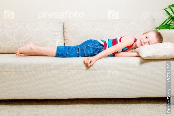 6 years old boy lying on the couch in the living room, stock photo