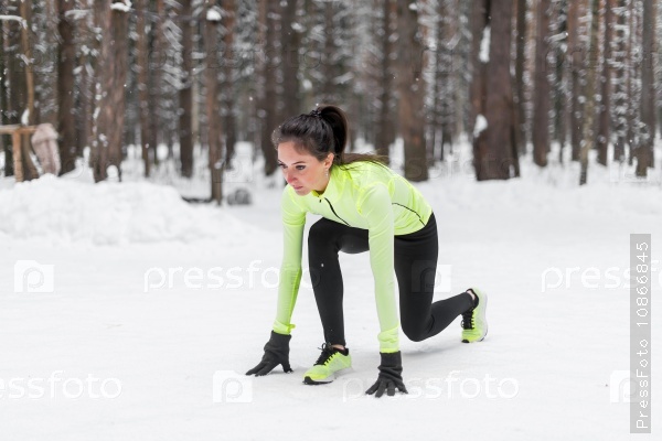 Fit woman in position ready to run outdoors winter park.