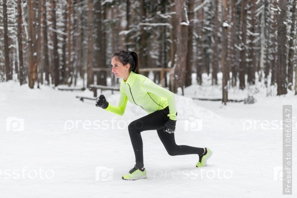 Девушка выполняет спортивные упражнения в зимнем парке
