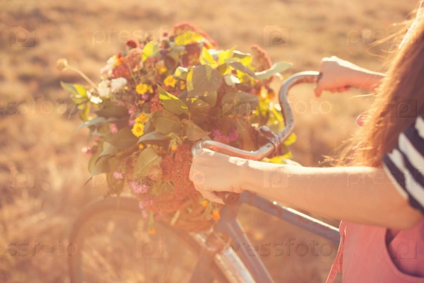 Girls arms holding an old bike handlebar with flowers basket