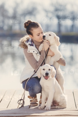 happy little girl with her dog golden retriever sitting on the bridge by the river. Cute little girl hugging golden retriever, smiling. The child with dogs. Puppies and child outdoor.