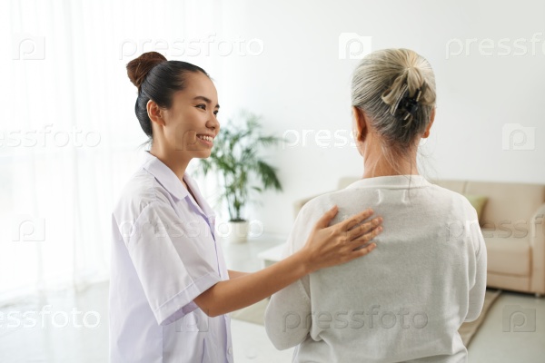 Nurse supporting aged woman