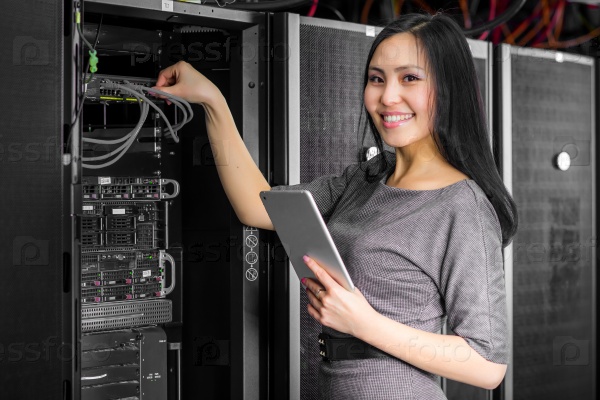 Young engineer businesswoman with tablet in network server room, stock photo