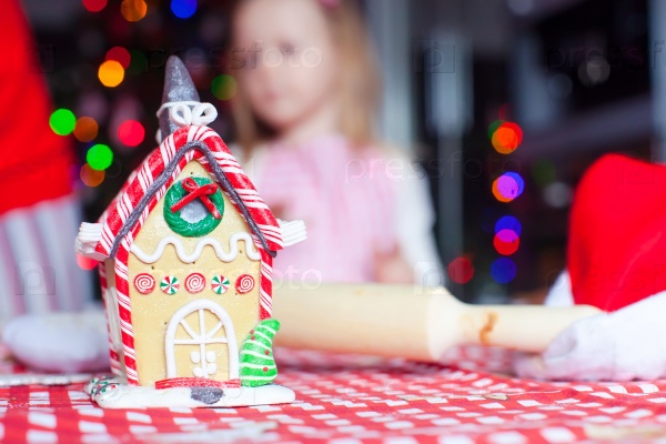 Gingerbread fairy house for Christmas on background of kids and fir-tree with garland, stock photo