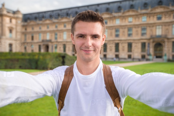 Young man taking a selfie photo outdoors in Paris, France, stock photo