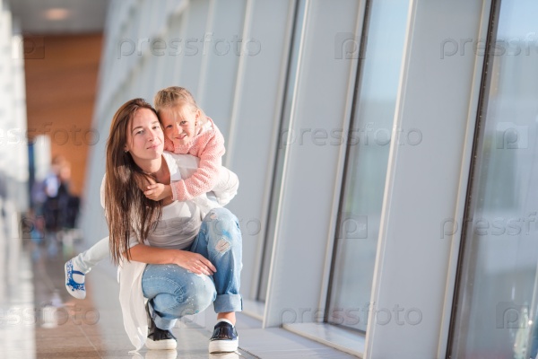 Happy family at airport sitting on suitcase with boarding pass waiting for boarding, stock photo