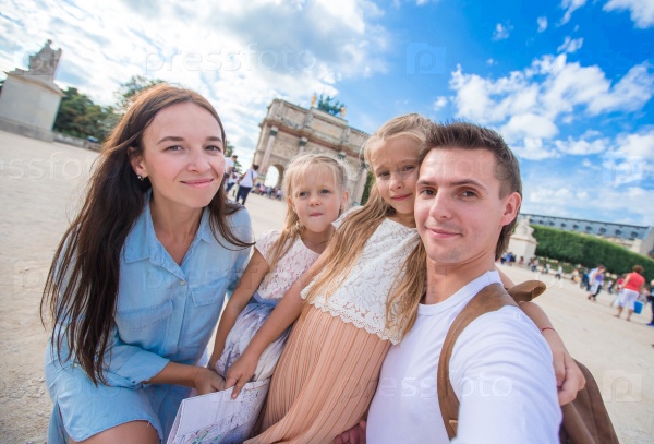 Happy young family with map of city taking selfie background famous Louvre in Paris, stock photo