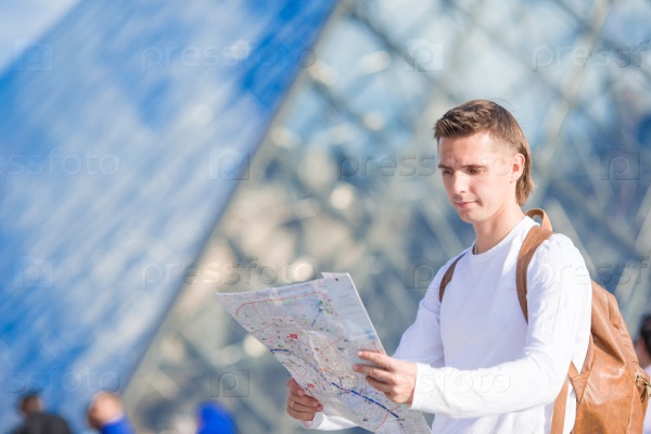 Happy young man with a city map in european city outdoors