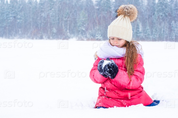 Portrait of little adorable happy girl in the snow sunny winter day, stock photo