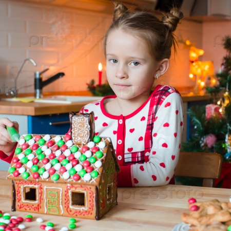 Little adorable girl with decorating gingerbread house for Christmas