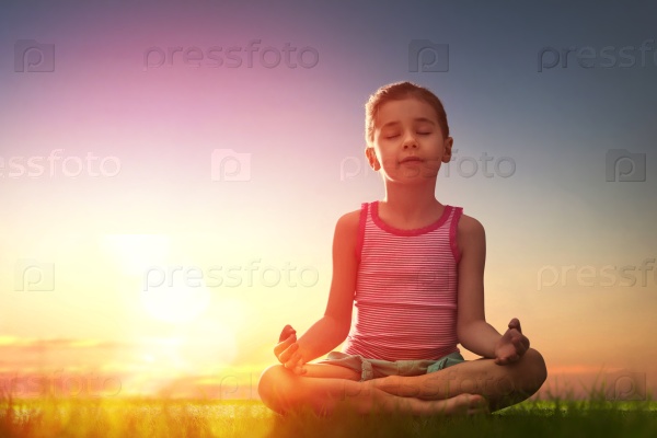 Child girl in the Park. Yoga at sunset in the park. Girl is practicing yoga.