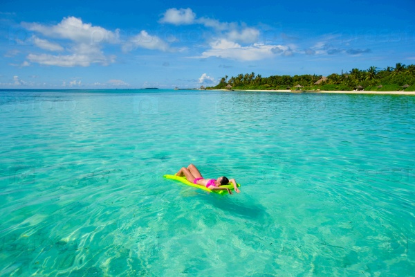 Woman relaxing on inflatable air mattress at turquoise water