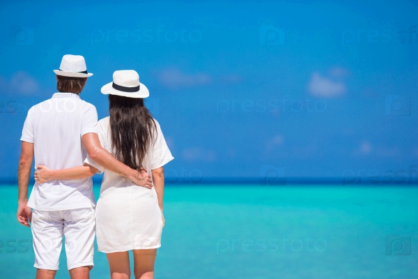 Back view of young couple on white beach at summer vacation
